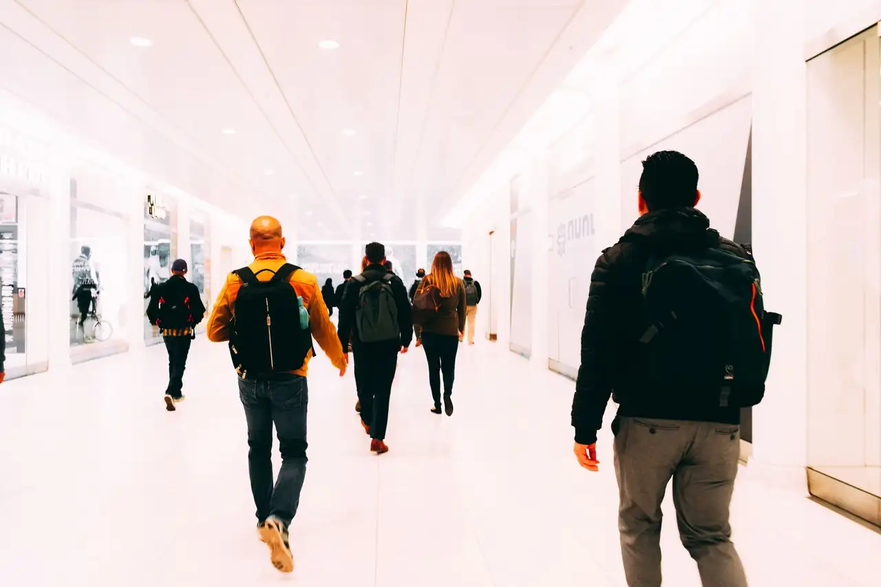Group of travelers walking through a bright, modern airport terminal carrying backpacks.