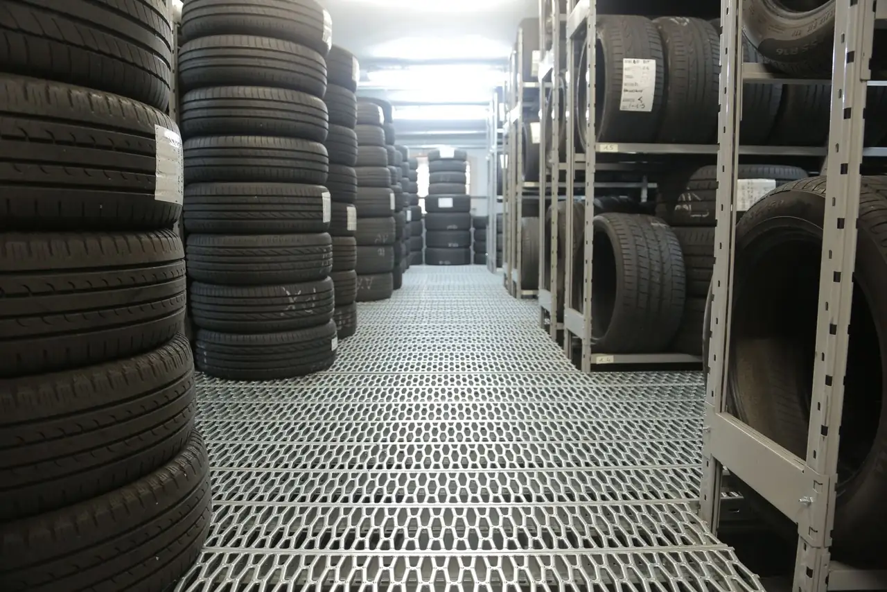 Rows of stacked tires in an indoor industrial warehouse for storage.