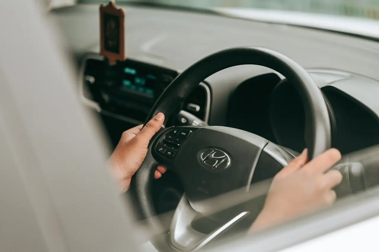 Close-up view of hands holding the steering wheel inside a car.